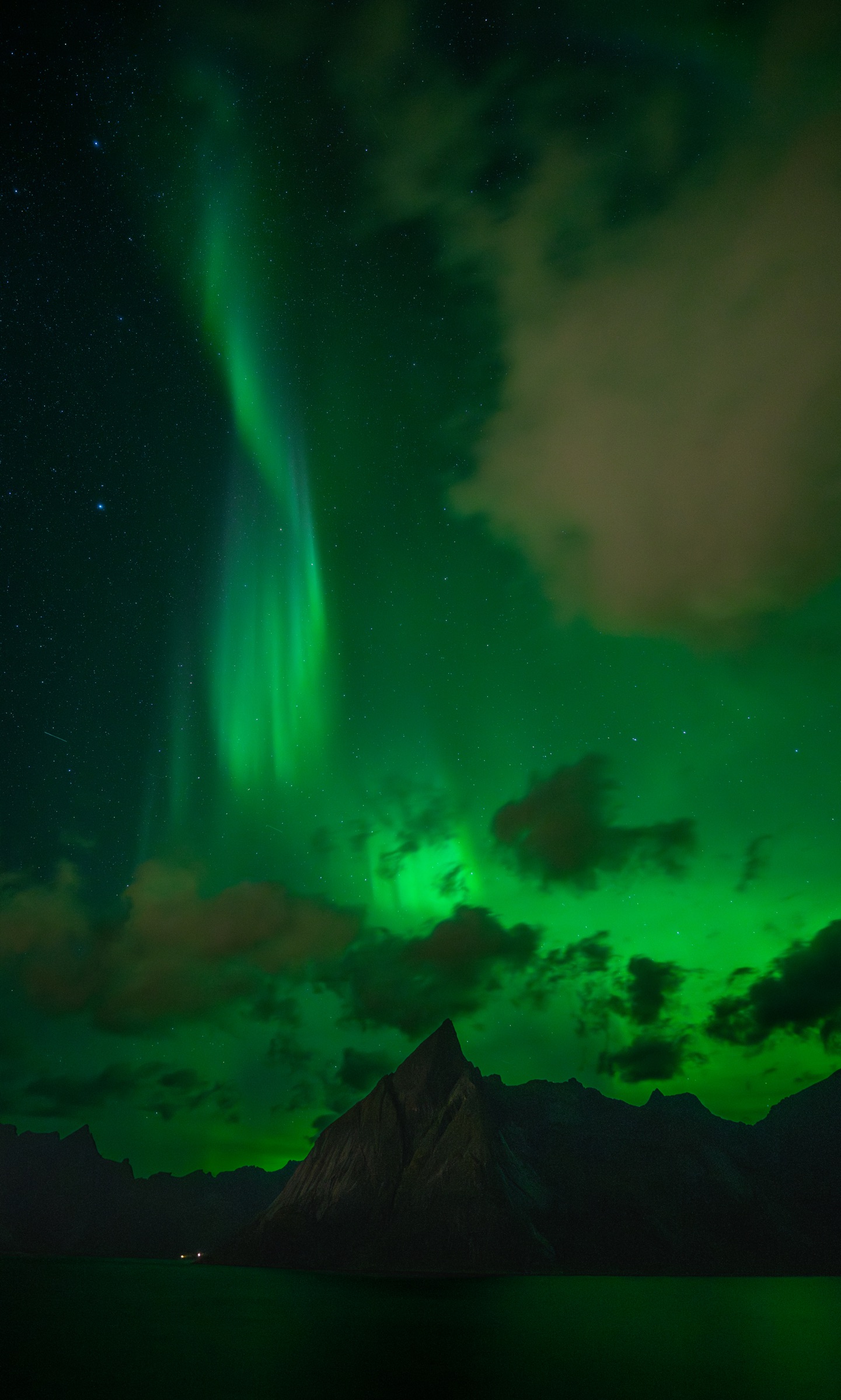 Green aurora dancing above a dark mountain