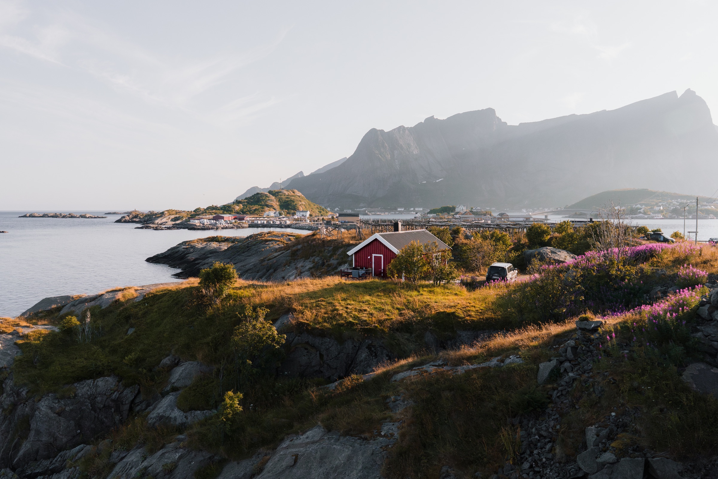 Red fishing cabins in a sunlit coastal landscape