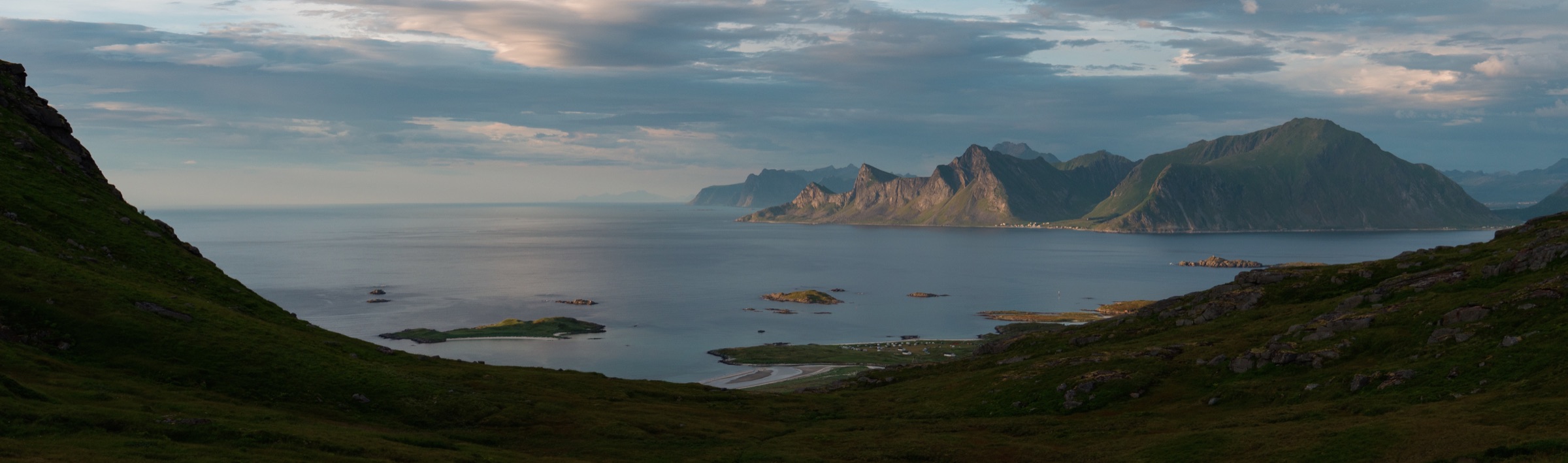 Wide view across a calm fjord towards distant mountains
