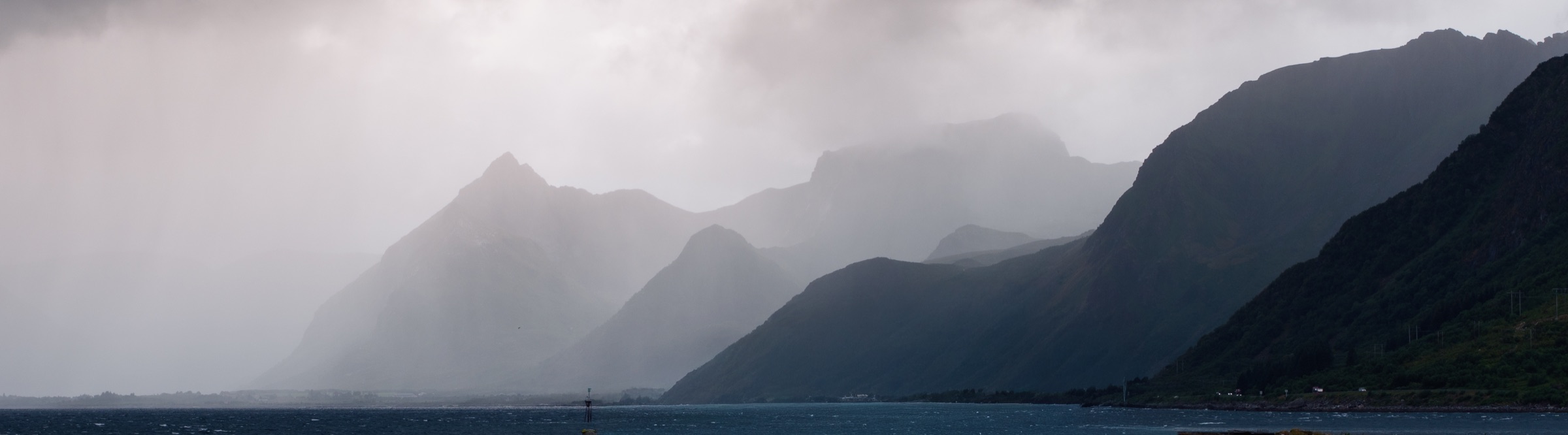 Misty mountain silhouettes along a Norwegian fjord