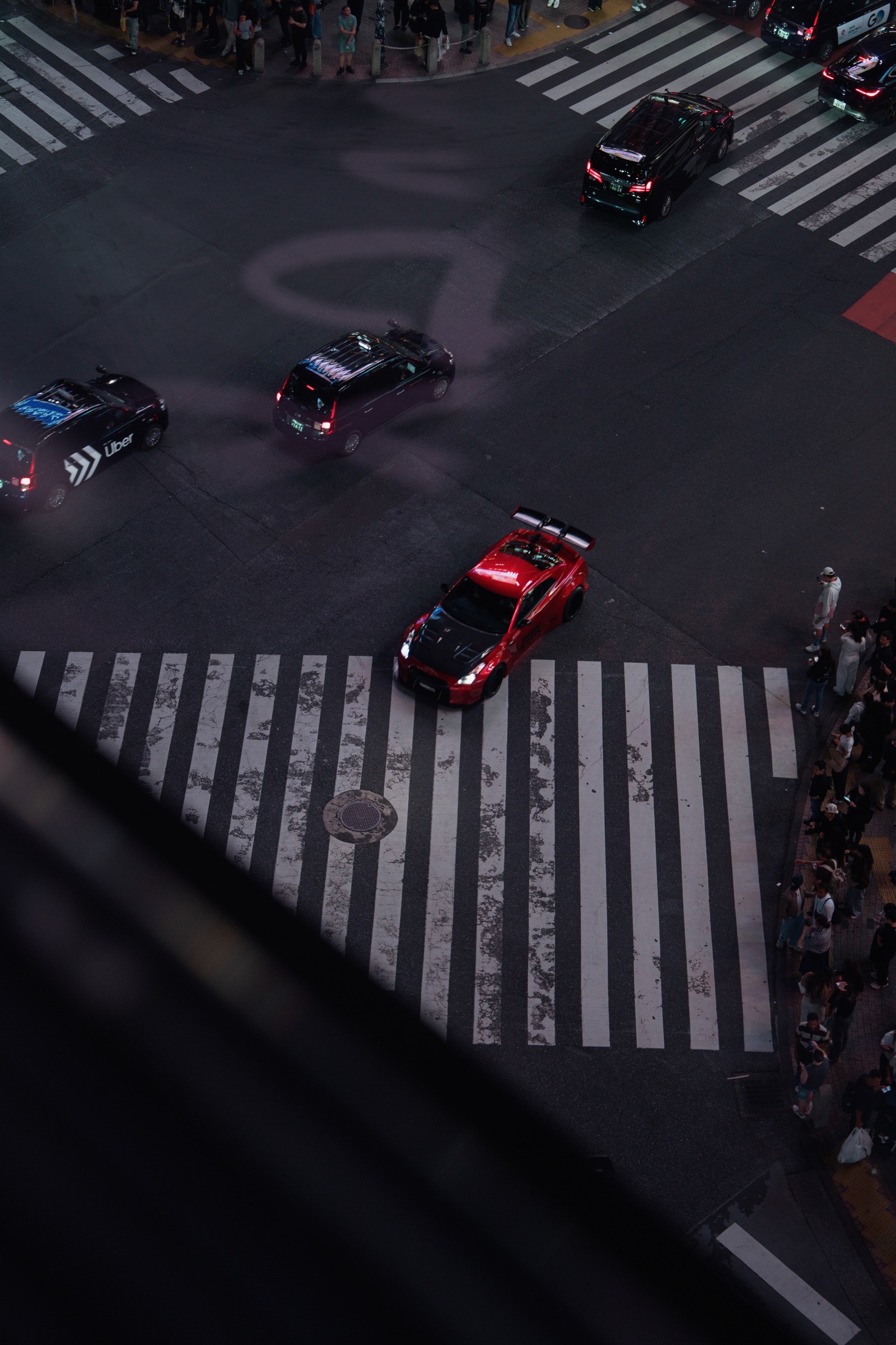 Cars crossing a geometric Tokyo intersection at night